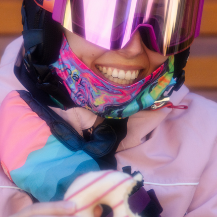 Chica comiéndose un doughnut con las gafas de esquí Sweet Avalanche.