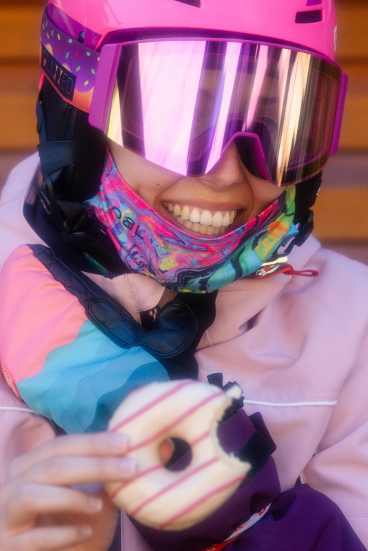 Chica comiéndose un doughnut con las gafas de esquí Sweet Avalanche.
